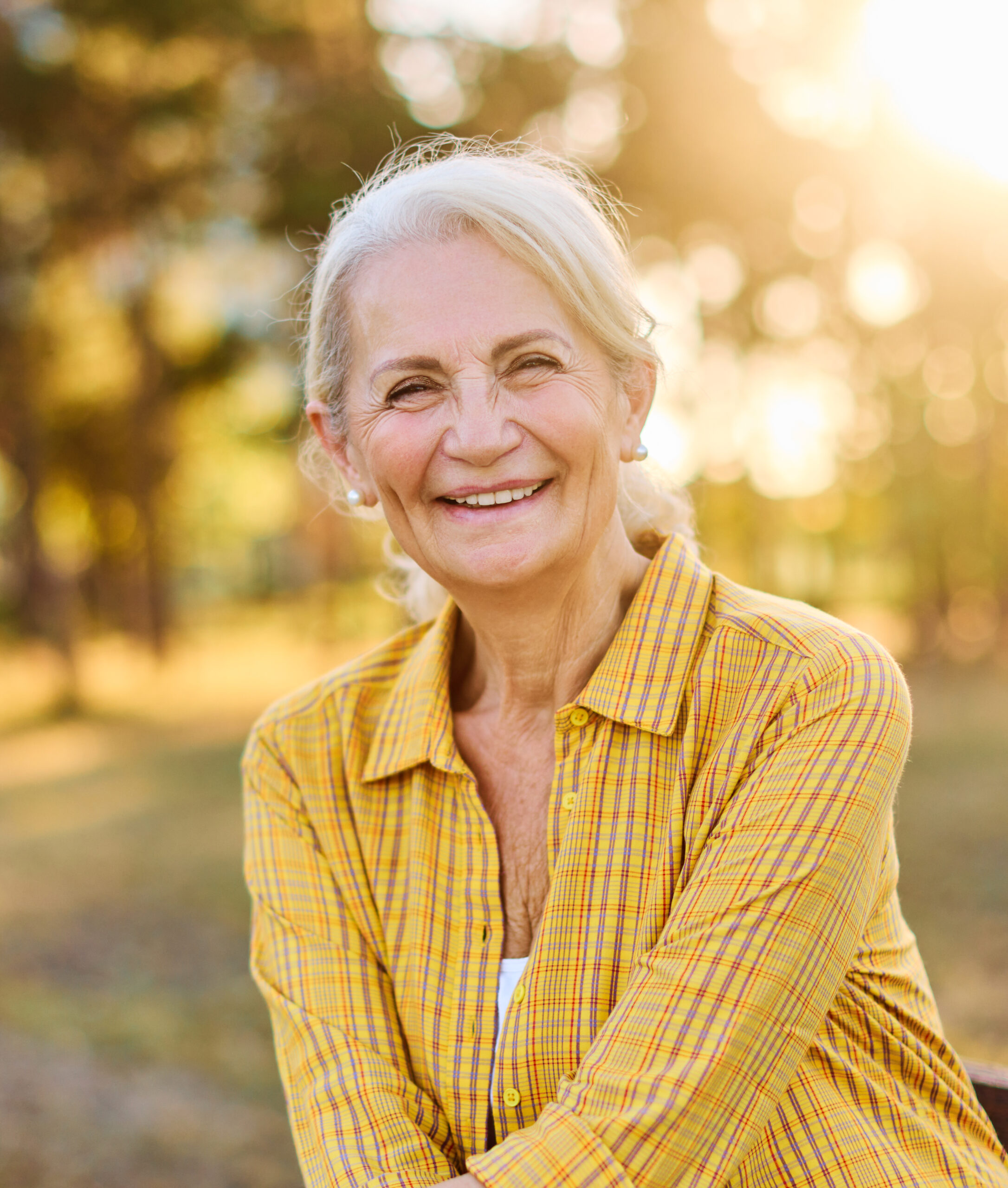 Portrait of an elderly woman outdoors. Happy senior woman sitting on a bench in park