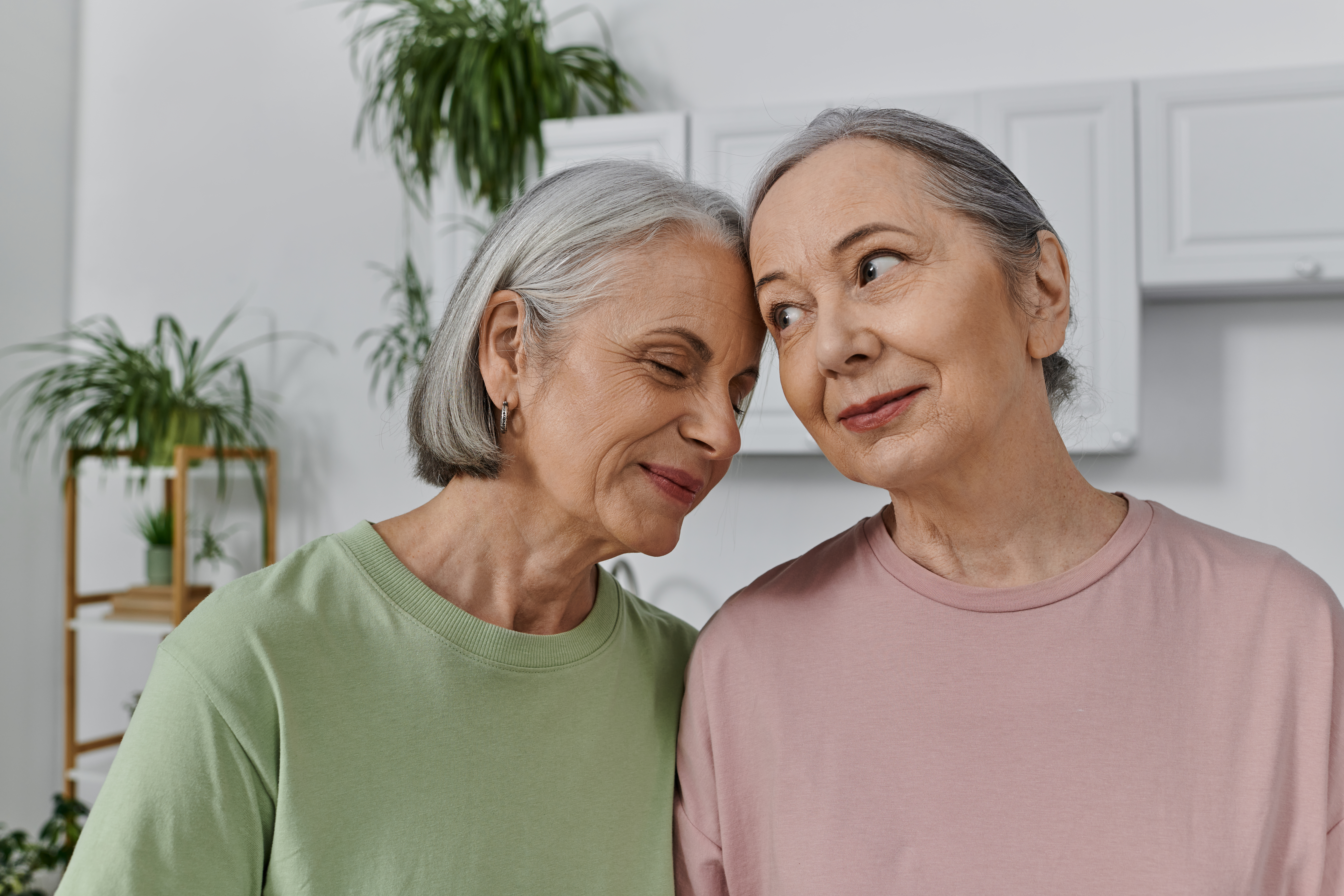 A mature lesbian couple shares a tender moment in their modern apartment, showcasing their love and connection.